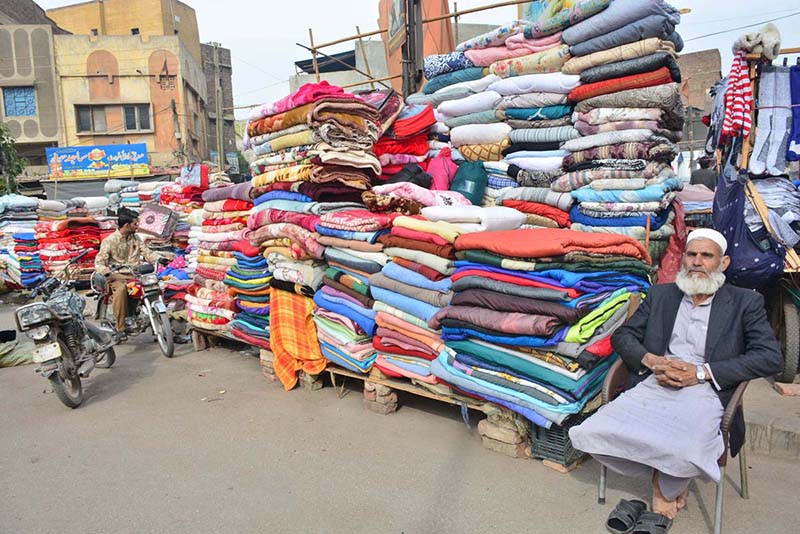 A vendor displaying the blankets to attract the customers on the footpath at bacha khan chowk