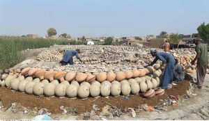 A worker arranging clay-made money boxes for drying purpose at Kumharpara, Jamshoro Road.