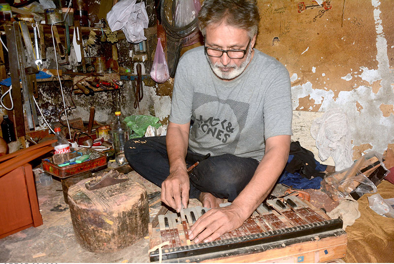 An artisan busy in repairing musical instrument (Harmonium) at his workplace