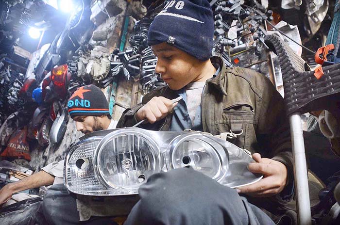 Youngster busy in repairing vehicle headlight at Shoba Bazar.