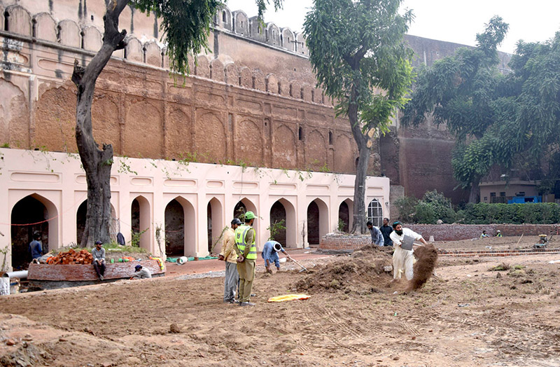 Labourers busy in restoration work on the wall of historical Shahi Qila