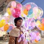 A young vendor displaying balloons to attract the customers at Railway Station Road