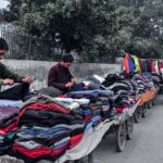 Vendors selling and displaying second hand warm clothes at their roadside setup
