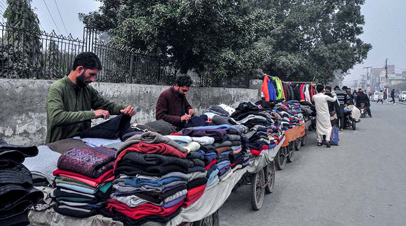 Vendors selling and displaying second hand warm clothes at their roadside setup