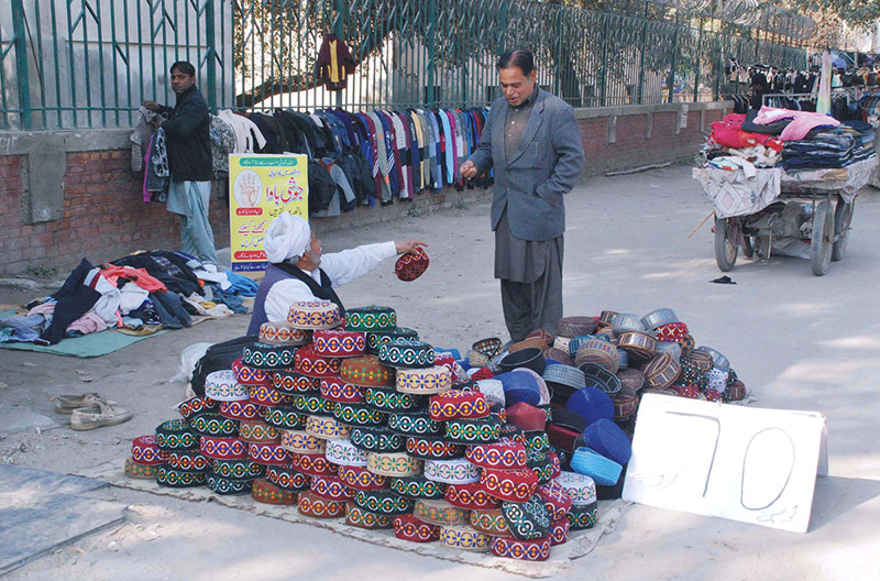 A vendor selling and displaying Sindhi hats at his roadside setup