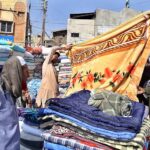 Vendor displaying blanket to attract the customer at station road