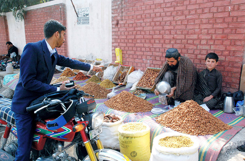 A vendor selling and displaying dry fruits at his roadside setup.