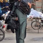 A street vendor displaying and selling jackets while shuttling on Hussain Agahi Road
