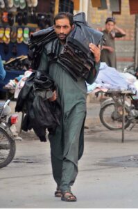 A street vendor displaying and selling jackets while shuttling on Hussain Agahi Road