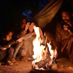 A family sitting around the fire to keep them warm as the temperature falls in the city.