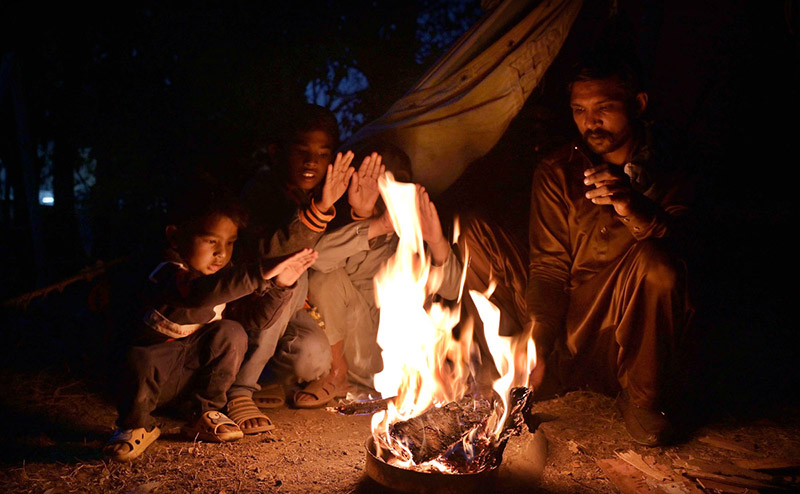 A family sitting around the fire to keep them warm as the temperature falls in the city.