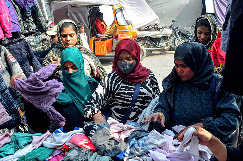 Customers selecting and purchasing second hand warm clothes from the roadside vendors