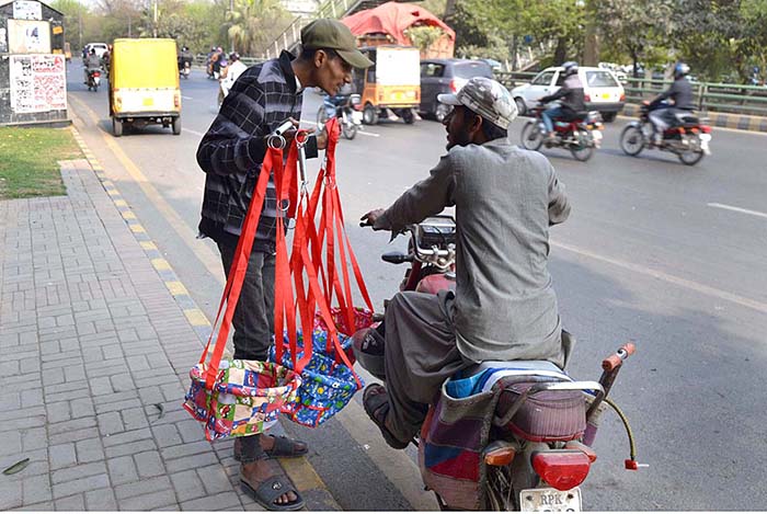 A vendor displaying hanging baby swings for children to attract customers at his roadside setup.