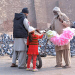 An elderly vendor selling cotton candy while shuttling on the road