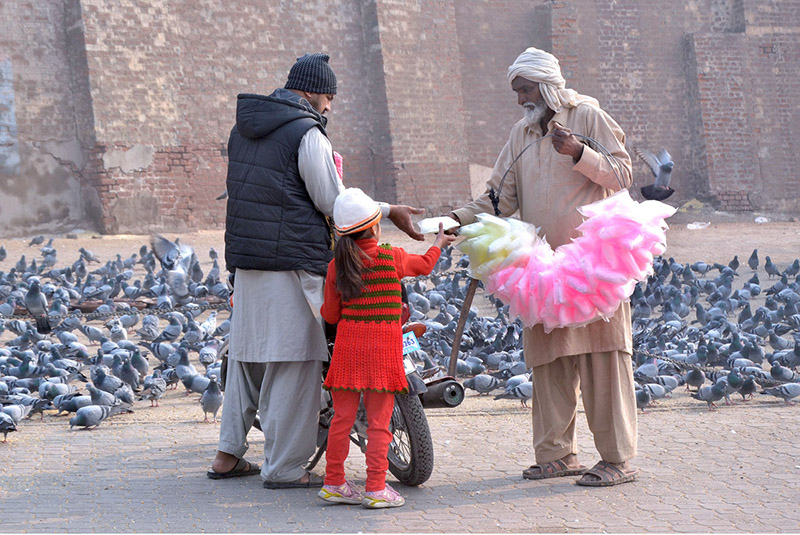 An elderly vendor selling cotton candy while shuttling on the road