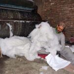 Laborer is busy in filling cotton in a pillow for selling purposes in the Gabgari area
