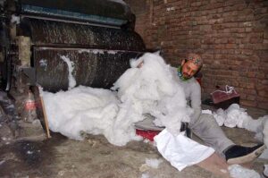 Laborer is busy in filling cotton in a pillow for selling purposes in the Gabgari area