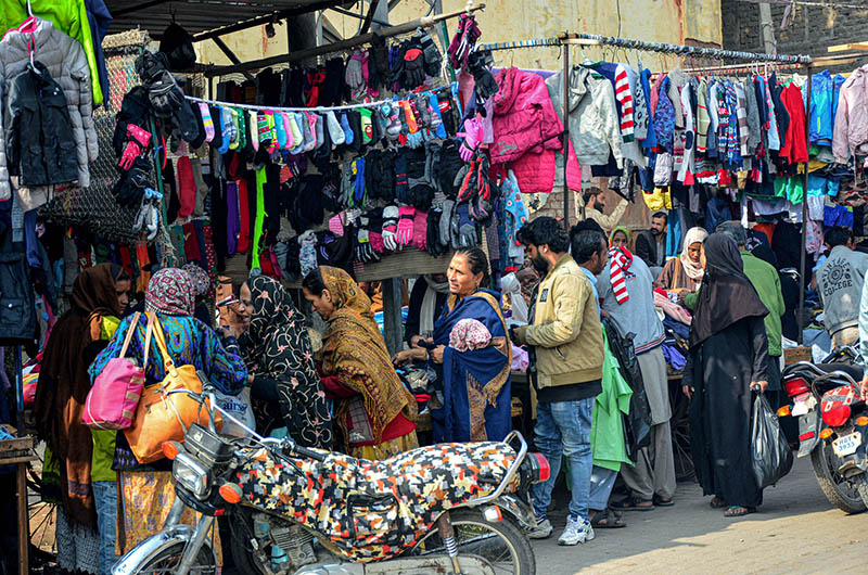 Customers selecting and purchasing second hand warm clothes from the roadside vendors