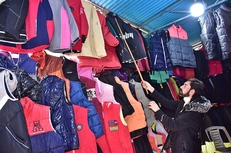 A vendor selling and displaying warm clothes at his shop