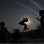 Gypsy children enjoying jump on trampoline during sunset at G-7 area