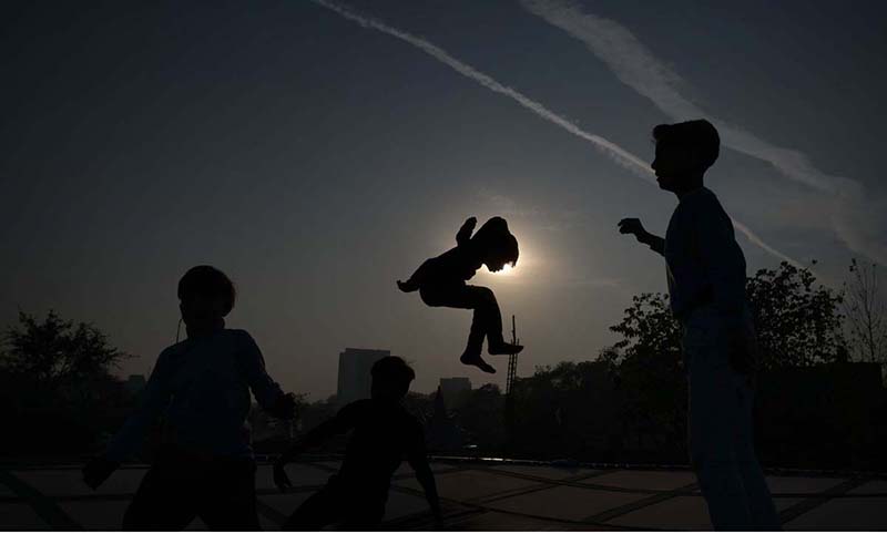 Gypsy children enjoying jump on trampoline during sunset at G-7 area