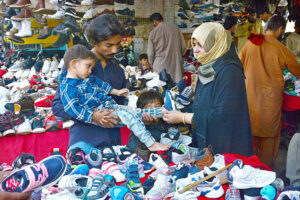 A couple selecting and purchasing second hand shoes for child from vendor at Station Road