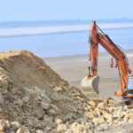 Labourer busy in repairing the embankment of Indus River with the help of machine at Husseinabad