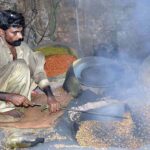 A worker busy in roasting grams for customers at his workplace.
