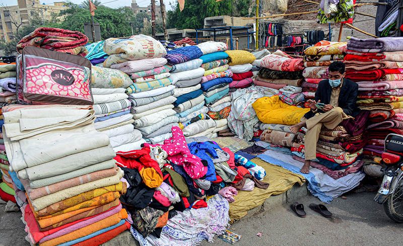 Customers selecting and purchasing second hand warm clothes from the roadside vendors