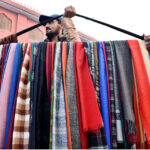A street vendor carrying the warm winter scarf for selling while shuttling on the road at Landa Bazar