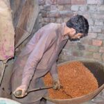 A worker is busy in roasting grams and peanuts at his setup
