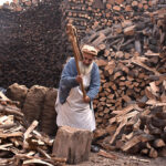 An elderly labourer cutting wood into pieces for selling purpose at his workplace