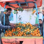 People purchasing orange from a push cart at Joint Road