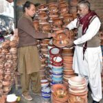 A person busy in selecting handmade clay pots at Qainchi stop