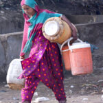Gypsy woman on the way while carrying pots for filling clean drinking water at Latifabad.