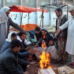 Vendors huddled around a fire due to the drop in temperature at Joint Road