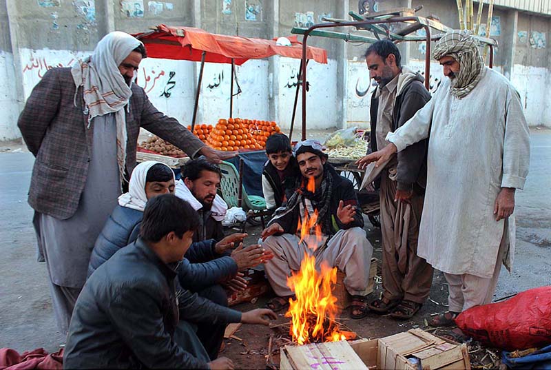 Vendors huddled around a fire due to the drop in temperature at Joint Road