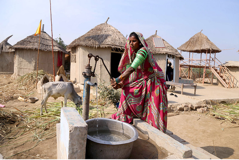 A villager lady filling water from a hand pump at the model of the Climate Resilience Markaz of bamboo housing by the Intellectual Property Organization, Government of Pakistan, in Pono village