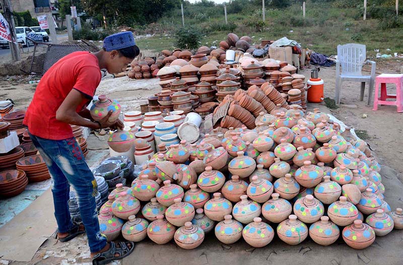 A vendor busy in arranging and displaying clay Golak (money boxes) to attract the customers at his roadside setup in Provincial Capital.