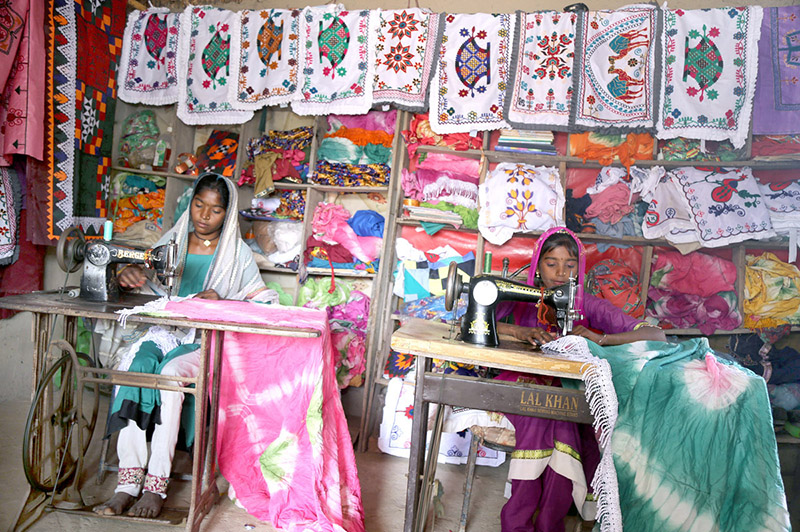 A villager lady filling water from a hand pump at the model of the Climate Resilience Markaz of bamboo housing by the Intellectual Property Organization, Government of Pakistan, in Pono village