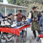 Customers purchasing shoes from roadside stall