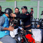 Chief Traffic Police Officer Dr. Zahid Ullah distributing helmets, mugs and history books of Quaid-e-Azam to a motorcyclist on the occasion of Quaid-e-Azam day at Khyber Road.