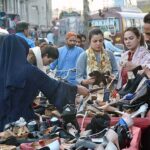 Women purchasing used shoes at a roadside stall