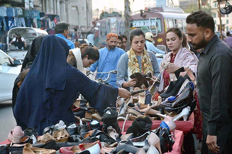 Women purchasing used shoes at a roadside stall
