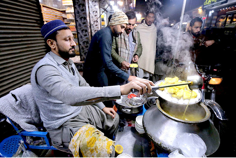 A vendor preparing warm traditional soup for a customer along a street during winter season in the Provincial Capital