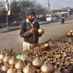 Vendor busy coloring clay made money boxes at roadside
