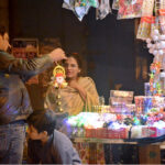 Women with children purchase shoes at a roadside stall ahead of Christmas