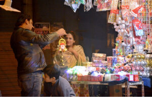 Women with children purchase shoes at a roadside stall ahead of Christmas