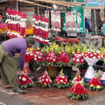 A shopkeeper is busy arranging and displaying flower bouquets to attract customers outside his shop
