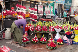 A shopkeeper is busy arranging and displaying flower bouquets to attract customers outside his shop